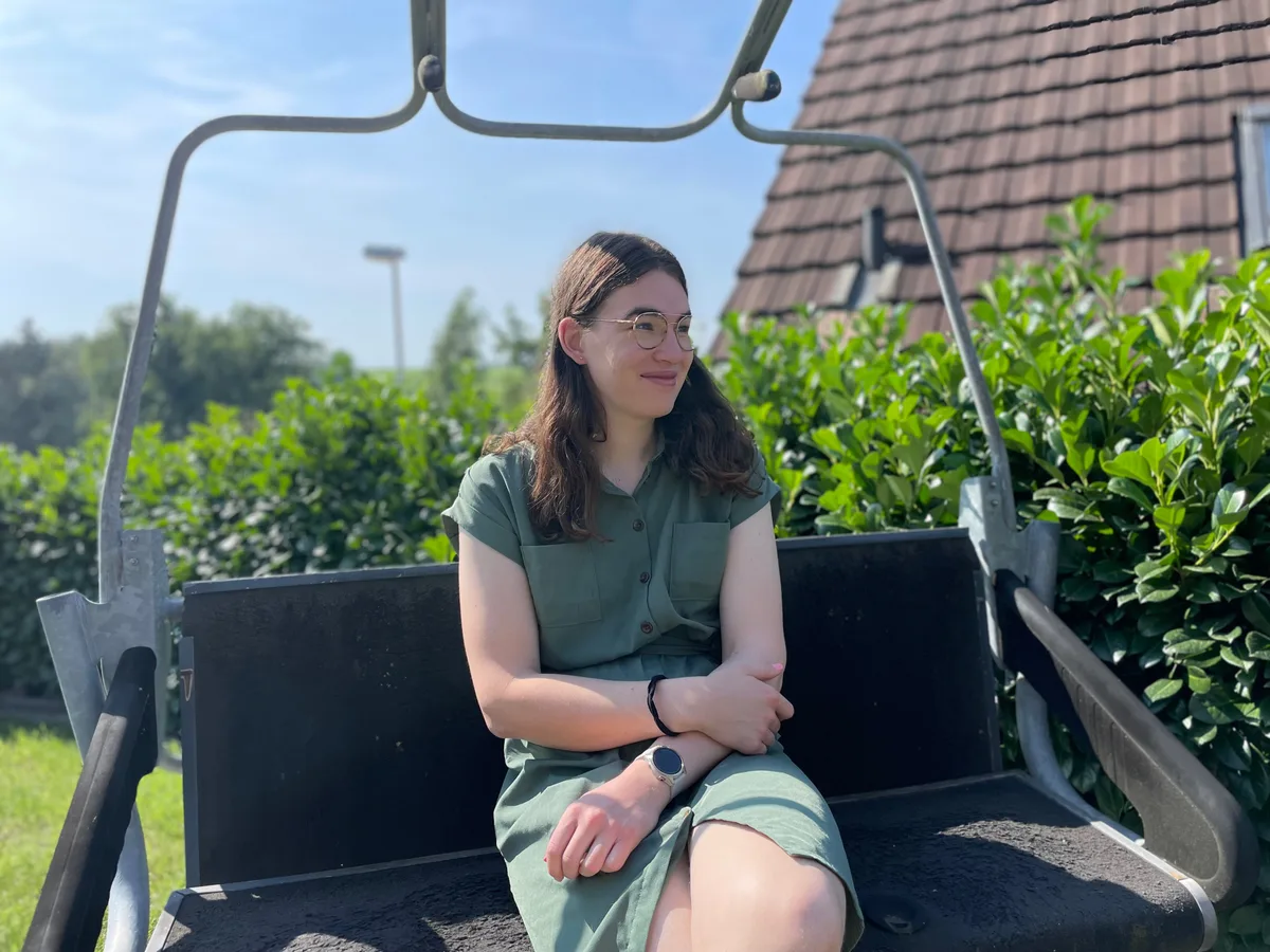 Für ihre Zukunft hat sie klare Ziele: Im nächsten Sommer will sie den Master machen und im Anschluss ein Doktorat. Eine junge Frau im grünen Kleid sitzt in ihrem Garten auf einem alten Sessellift.